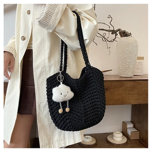 Detailed view of black woven tote bag with a white plush cloud pendant in a lifestyle setting
