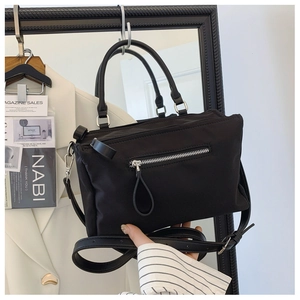 Detail of black nylon crossbody bag with silver metal zipper and adjustable strap