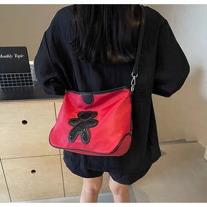 Sac bandoulière rouge avec un ours en paillettes noires et des bretelles élégantes