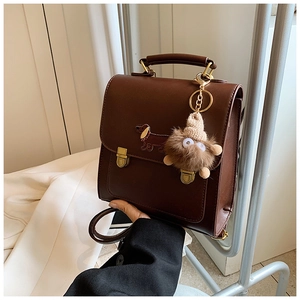 Detail of dark brown retro PU leather handbag with dachshund embroidery and plush charm