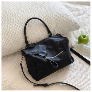Close-up of a black nylon crossbody bag on a white waffle texture surface with natural light