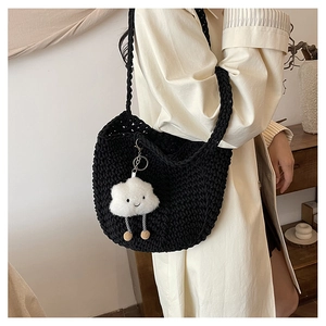 Detail of hand-woven black crochet shoulder bag with a cute white plush cloud charm