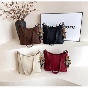 Litchi pattern bucket bags in four colors with bear charms on minimalist display
