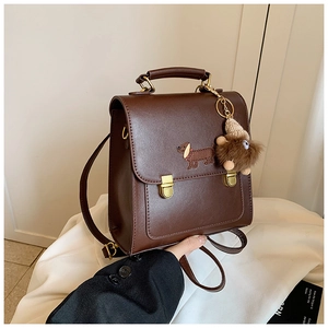 Detail of dachshund embroidery and plush charm on dark brown leather backpack
