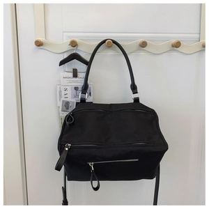 Macro view of multi-zipper black nylon crossbody bag with premium leather pullers