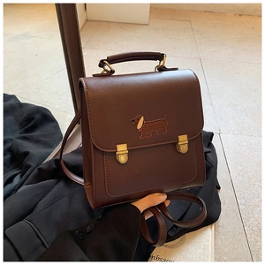 Detail of vintage dark brown PU leather backpack with cute dachshund embroidery and buckles