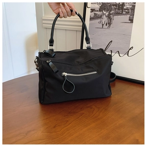 Close-up of black nylon handbag featuring silver zipper details and sturdy round handle