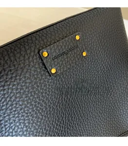 Close-up of black pebble leather bucket bag with gold rivets and embossed logo detail