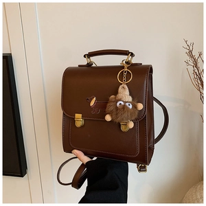 Detail of dark brown vintage mini backpack with dachshund embroidery and plush charm