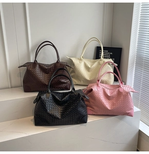 Detail of woven leather tote bags in brown, beige, black, and pink colors on marble
