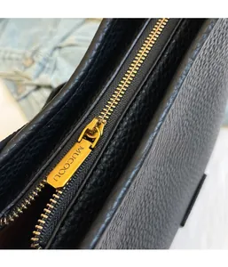 Close-up of golden metal zipper detail on black lychee grain leather bucket bag