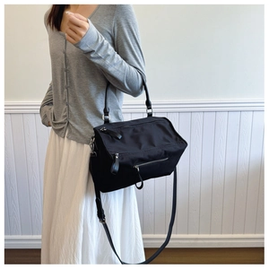 Detail shot of black nylon crossbody bag on model with multiple metal zippers and adjustable strap