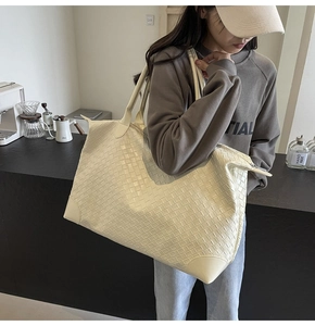 Detail view of woven leather texture and reinforced base corners on large cream tote bag