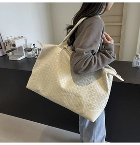 Detail of cream woven leather tote bag showing large capacity and textured pattern