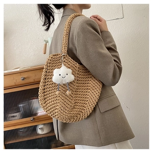 Detail of woven tote bag texture with cute plush cloud pendant and braided shoulder strap