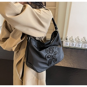 Détail du sac de voyage en nylon noir avec ours en paillettes et bandoulière large