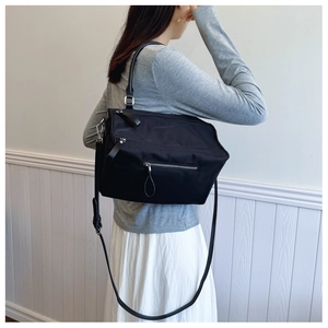 Fashion model wearing a black nylon multi-pocket crossbody bag with adjustable straps