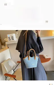 Detail of light blue denim bucket bag with brown leather handles and shoulder strap