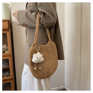 Detailed texture of hand-woven shoulder bag with cute cloud plush charm pendant