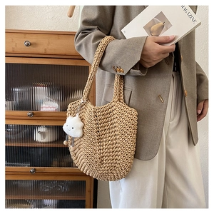 Detail of khaki woven tote bag with a cloud charm and bohemian braided texture