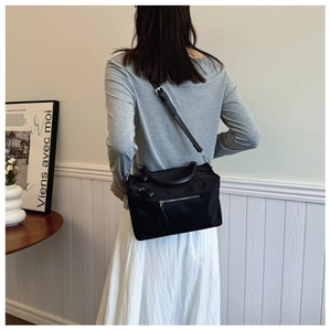 Rear view of black nylon crossbody bag featuring silver zipper and adjustable strap