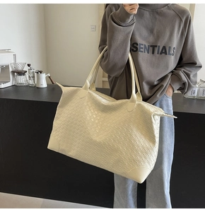 Close-up of the woven leather texture and reinforced corners on the beige tote bag