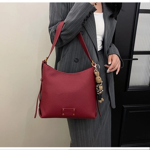 Detail of burgundy lychee leather hobo bag with gold plate and cute bunny pendant charm