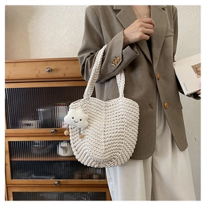 Detail of hollow woven tote bag in cream white with a cute cloud charm accessory