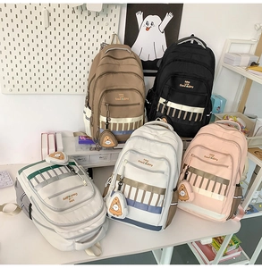 Détail de sacs à dos scolaires en cinq couleurs avec pendentif pizza sur un bureau d'étude