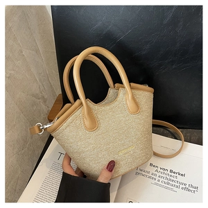Detailed close-up of woven bucket bag featuring brown leather handles and brand logo