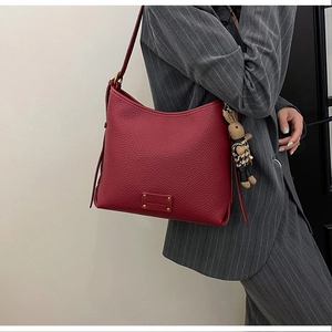 Detail of burgundy lychee leather bucket bag with metal logo and houndstooth rabbit charm