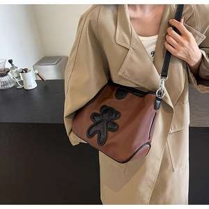 Détail d'un sac de voyage marron en similicuir avec patch ours et bordures noires