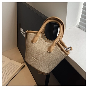 Detailed view of woven bucket bag featuring brown leather trim and silver metal hardware