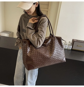 Detailed view of dark brown woven tote bag with leather piping and dual shoulder straps