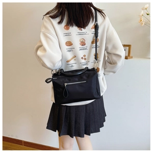 Rear view of a black nylon crossbody bag with zipper pocket shown on model