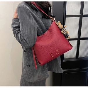 Close-up of dark red bucket bag in litchi grain leather with cute rabbit charm