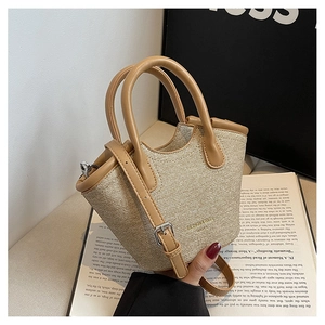 Detail of a minimalist mini tote bag featuring beige fabric and camel leather accents