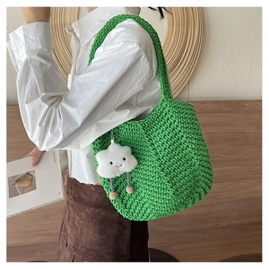 Detailed knit texture of a bright green woven tote bag with a plush cloud charm accessory