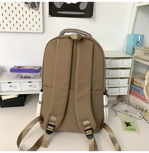 Détail des bretelles rembourrées et du tissu en nylon marron imperméable du grand sac à dos
