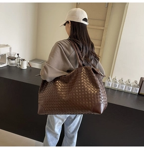 Detail of a dark brown woven leather tote bag shown in a stylish cafe setting