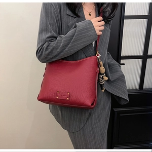 Detail of red lychee textured leather bucket bag with gold hardware and rabbit charm