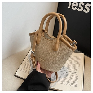 Detail of a mini woven bucket bag with camel leather handles and a fine shoulder strap