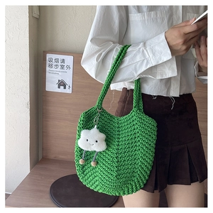 Detailed knit texture of green crochet shoulder bag with plush cloud charm detail