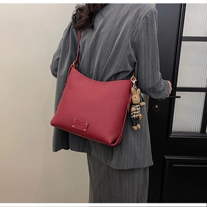 Detail of dark red lychee grain leather bucket bag with cute bunny charm on model
