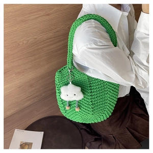 Detail of green hand-knitted tote bag featuring thick woven texture and cloud charm