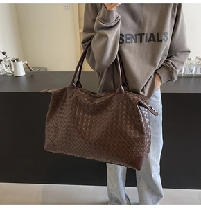 Detailed close-up of dark brown woven leather tote bag with reinforced bottom corners