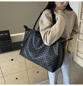 Detail of black woven leather tote featuring reinforced corners and large capacity design