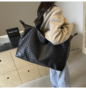 Detailed view of black woven tote bag with adjustable shoulder strap for travel