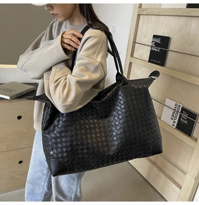 Detail of hand-woven leather texture on large black tote bag carried by a model
