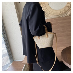Detail of straw tote bag showing natural woven texture and brown leather strap handles